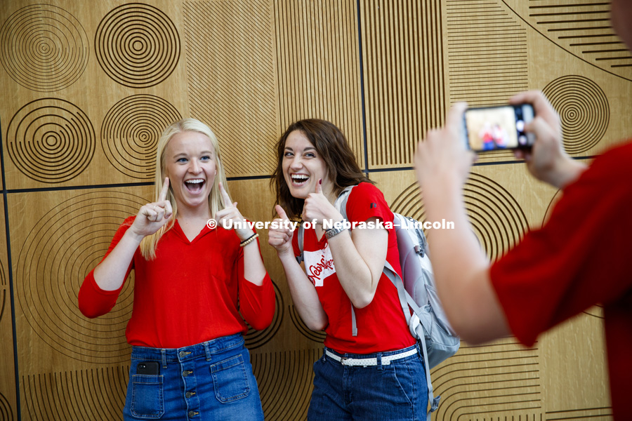 Two young women pose in front of the art wall in the Massengale Residence Center as their friend snaps a picture of them on his phone. CASNR photo shoot on East Campus. May 29, 2018. Photo by Craig Chandler / University Communication.