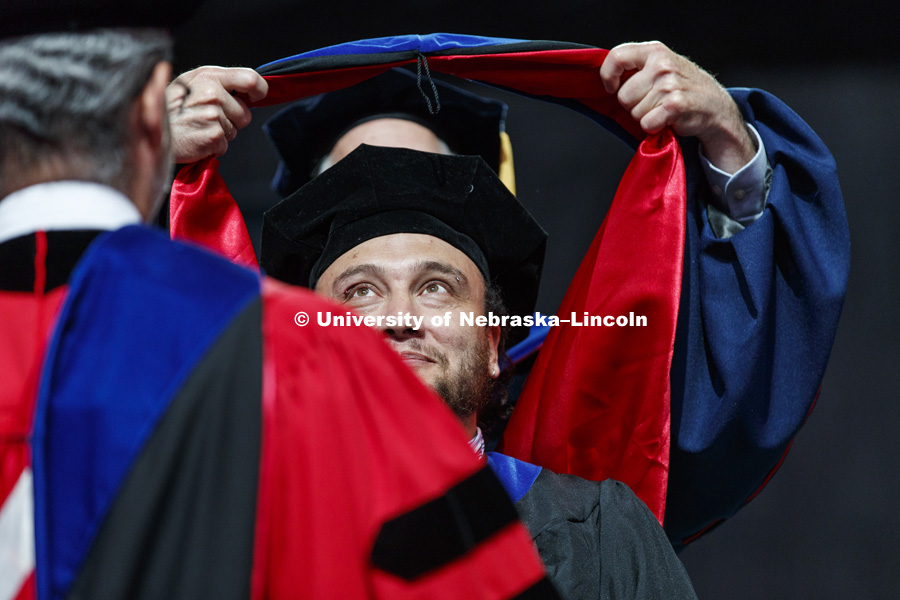 Jose Monroy has his eye on the prize as his doctoral hood is draped over his head. Summer Commencement at Pinnacle Bank Arena. August 11, 2018. Photo by Craig Chandler / University Communication.