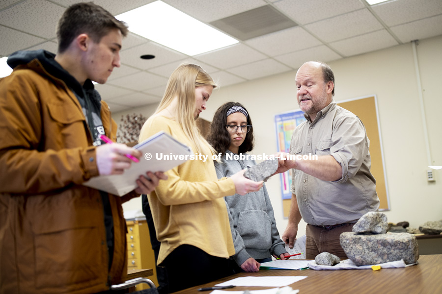 David Harwood answers the questions of Ariel Meyer, center, freshman from Wisner, and Bella Zeljko, freshman from Lincoln. Harwood teaches GEOL 125 - Frontiers in Antarctic Geosciences.  Class is classifying rocks and will then add them to their geologic timelines. December 3, 2018. Photo by Craig Chandler / University Communication.