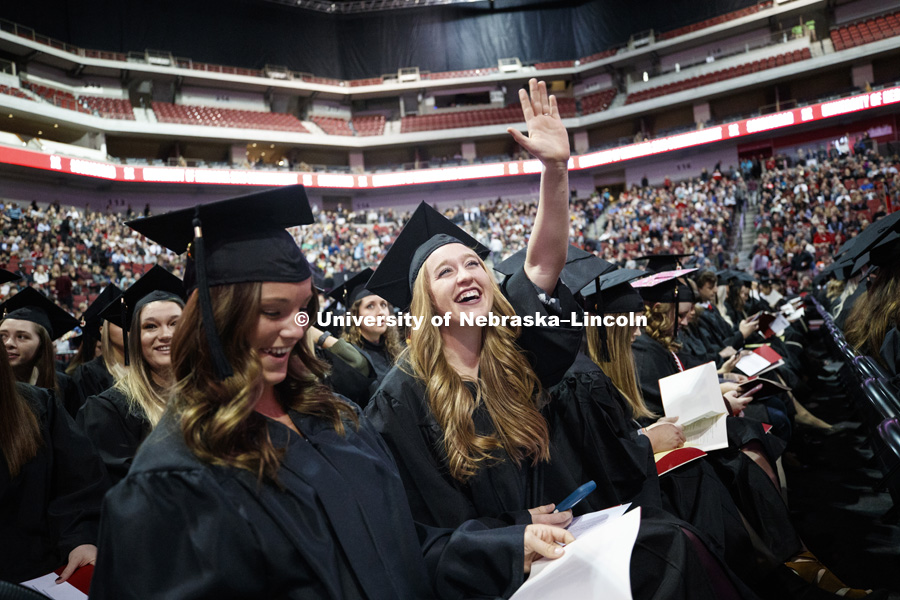 Delaney McFadden waves to her family and friends after taking her seat on the arena floor at the Undergraduate Commencement in Pinnacle Bank Arena. December 15, 2018. Photo by Craig Chandler / University Communication.
