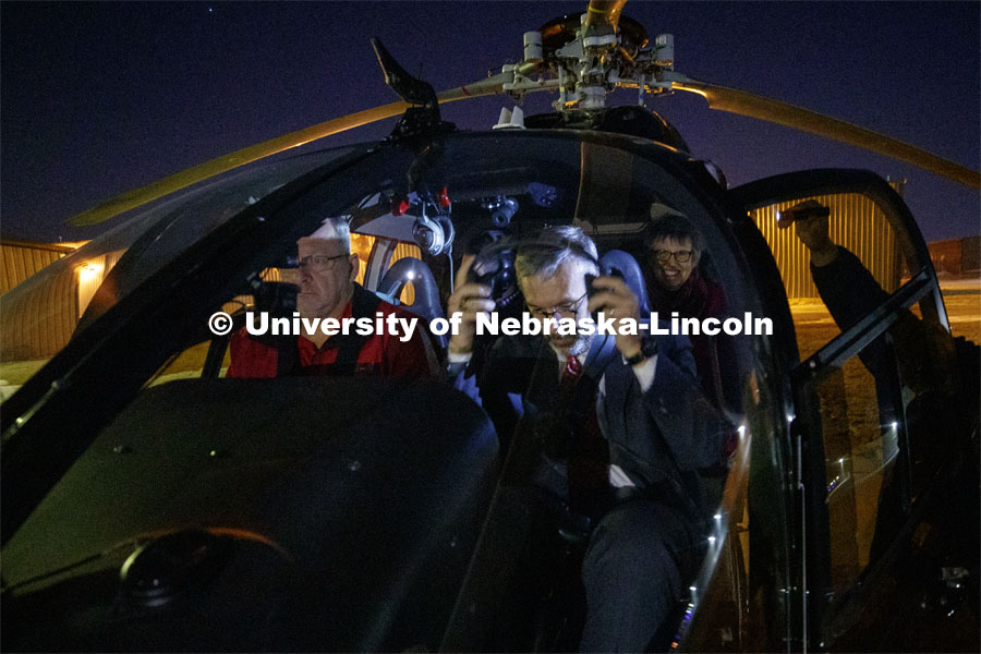 Chancellor Ronnie Green puts on a headset as he, his wife, Jane, and son, Nathan, prepare for a flight by Husker Helicopter's Kim Wolfe at left. Glow Big Red bathes the campuses with red lights as part of N150's Charter Week celebration. February 14, 2019. Photo by Craig Chandler / University Communication.