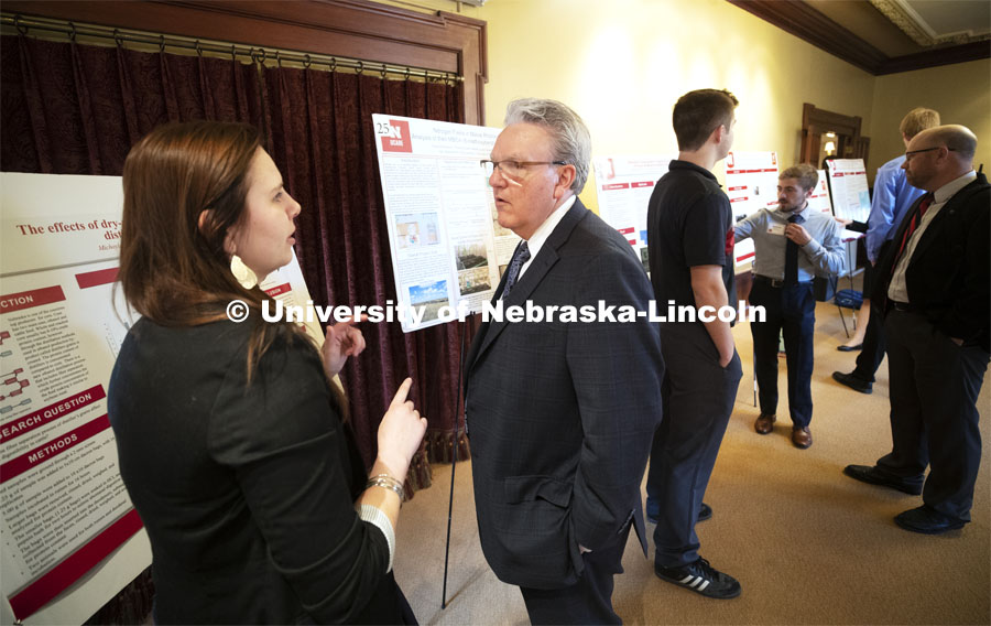 Michayla Goedeken of Madison explains her poster to Senator Jim Scheer of District 19. This year's research day at the capitol was held at the neighboring Ferguson House. Goedeken is researching the effects of dry-milling process on protein digestion of distillers grains in beef cattle. State Senators Research Fair at the Ferguson House. April 16, 2019. Photo by Craig Chandler / University Communication.