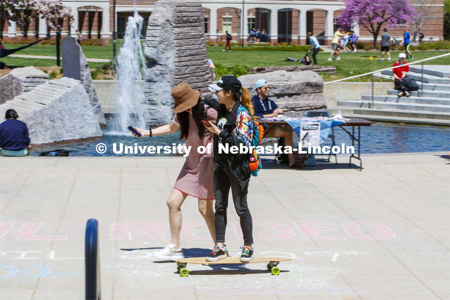Hanchen Zhang gets a free ride on her skateboard as her friend, Sihui Li walks her along the plaza by the fountain.