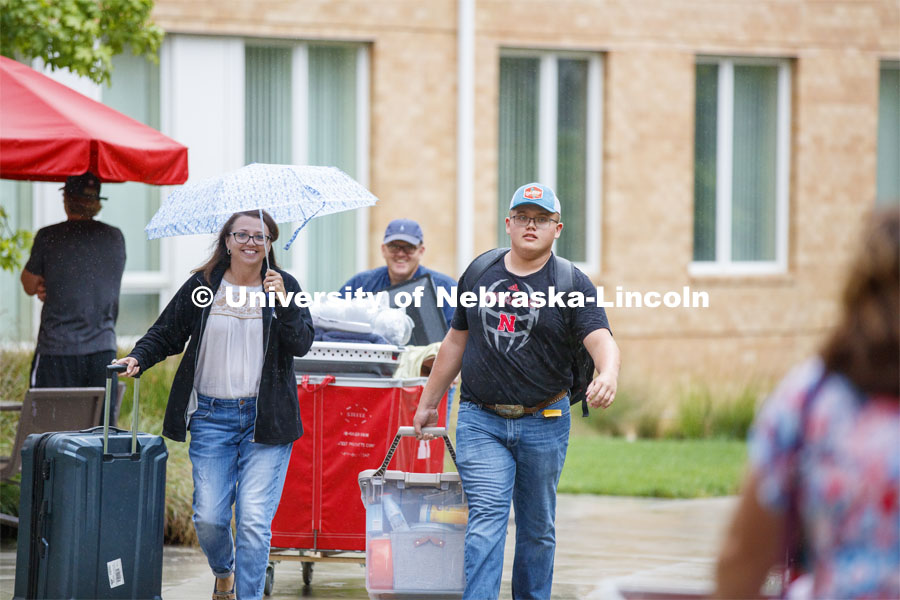 Tristan Smith carries his belongings as he moves in with the help of mom, Tina, and dad, Doug.  They are from Curtis, Nebraska. Massengale Residential Center move in. August 21, 2019. Photo by Craig Chandler / University Communication.