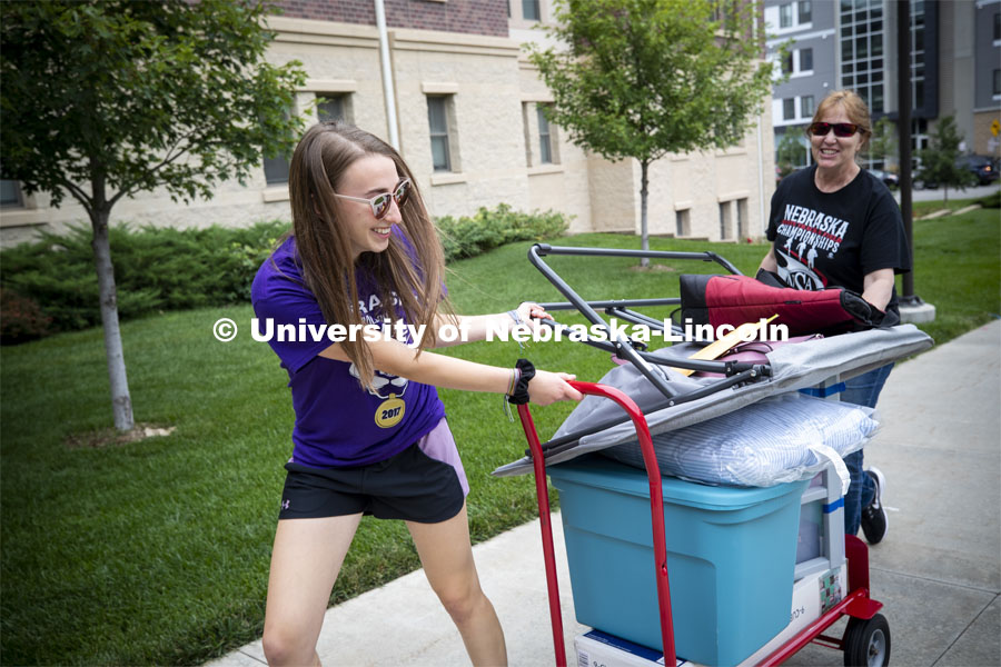 Taylor Hickey, a freshman from Elwood, Nebraska, laughs as she and her mom, Karma, try to keep her chair atop her loaded cart. Residential hall move-in to the Knoll Residential Center and University Suites. August 22, 2019. Photo by Craig Chandler / University Communication.