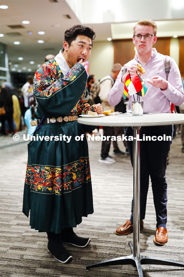 William Yao, left, and Andrew Neill sample food at the festival. Yao is wearing the undergarment for a Chinese Ming Dynasty court clothing. Global Huskers Festival, a multicultural festival provides attendees the chance to explore the world through informational booths that will have food, cultural décor, art, and more, each hosted by UNL students from those culture. November 19, 2019. Photo by Craig Chandler / University Communication.
