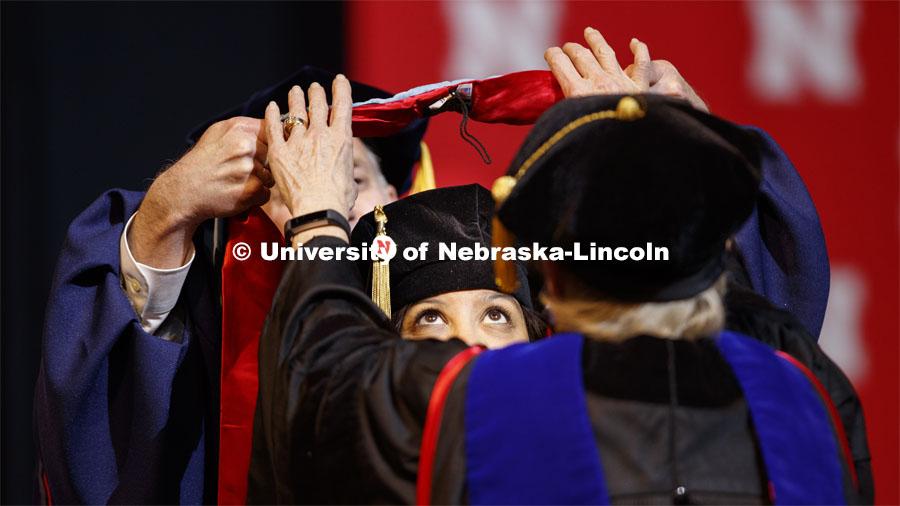 Brandi Bibins-Redburn has her eyes on the prize as her Doctor of Education hood is lowered over her head. Graduate Commencement and Hooding at the Pinnacle Bank Arena. December 20, 2019. Photo by Craig Chandler / University Communication.