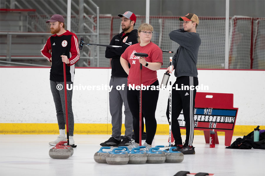 Members: Colin Wooldrik in the purple cap, Adam Schlichtmann in the red and gray cap, Anna Fiala in the Husker red tee shirt and Jordan Monk in the gray long sleeve shirt of the UNL Curling Team. Nebraska's nationally-ranked curling club host its first bonspiel at the John Breslow Ice Hockey Center this weekend. The bonspiel — or tournament — featured seven traveling schools from across the Midwest. February 1, 2020. Photo by Gregory Nathan / University Communication.