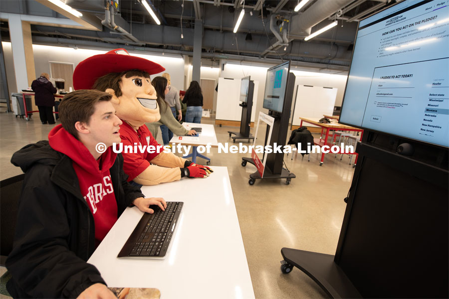 Herbie helps Elijah Hoefer digitally sign and print out the CEO Action Diversity and Inclusion Pledge at the Johnny Carson Center for Emerging Media Arts. February 5, 2020. Gregory Nathan / University Communication.