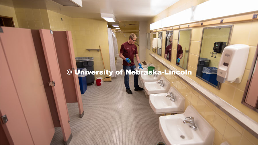 Patrick Bomberger, Residence Hall Custodial Leader sanitizes a bathroom inside of Piper Hall. March 16, 2020. Photo by Gregory Nathan / University Communication.