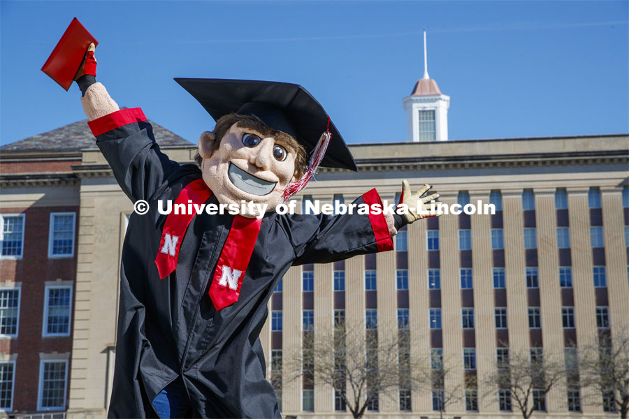 Herbie Husker leaps for joy on the lawn in front of Love Library and is decked out in graduation attire for the Spring Commencement that was which streamed online and aired on NET because of the COVID-19 pandemic. April 10, 2020. Photo by Craig Chandler / University Communication.