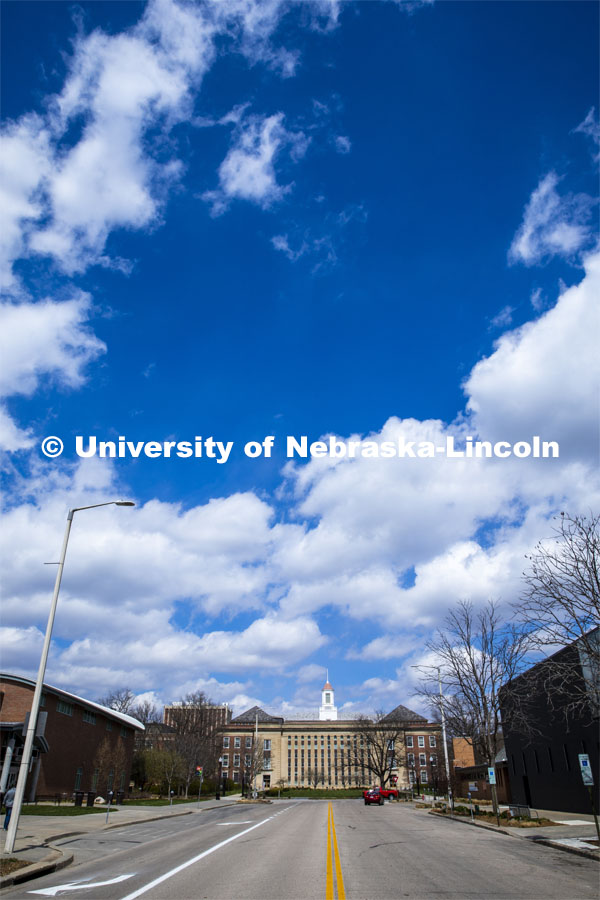 Fluffy clouds dot the sky above Love Library on City Campus looking north on 13th Street. April 14, 2020. Photo by Craig Chandler / University Communication.