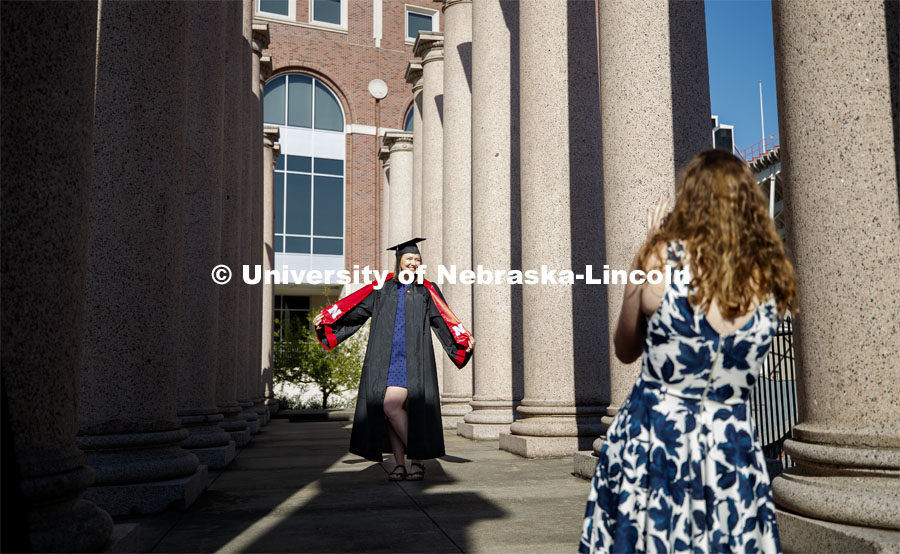 Rose Wehrman, senior in English, from Kenesaw, NE, is photographed by Sarah Schilling, senior in marketing from Omaha. The two borrowed a cap and gown (from a friend who graduated last year) to take photos of each other on campus Thursday morning. April 30, 2020. Photo by Craig Chandler / University Communication.