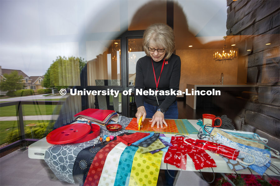 Joy Shalla Glenn, volunteer for the Quilt Center, cuts fabric for masks in her living room. She says she lost count how many she has made after 900. May 21, 2020. Photo by Craig Chandler / University Communication.