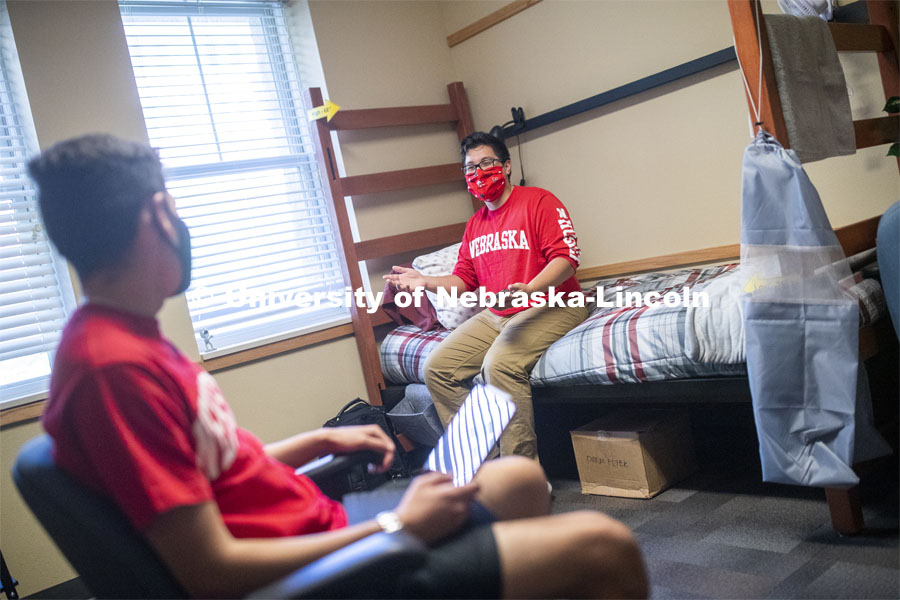 PJ Miguelino talks with Edwin Mendez-Rodriguez in a University Suites Residence Hall room. Photo shoot of students wearing masks and practicing social distancing. June 24, 2020. Photo by Craig Chandler / University Communication.