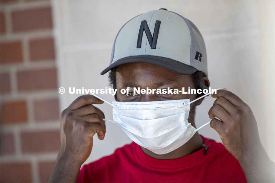 Mark Iradukunda puts on a mask. Photo shoot of students wearing masks and practicing social distancing. June 24, 2020. Photo by Craig Chandler / University Communication.