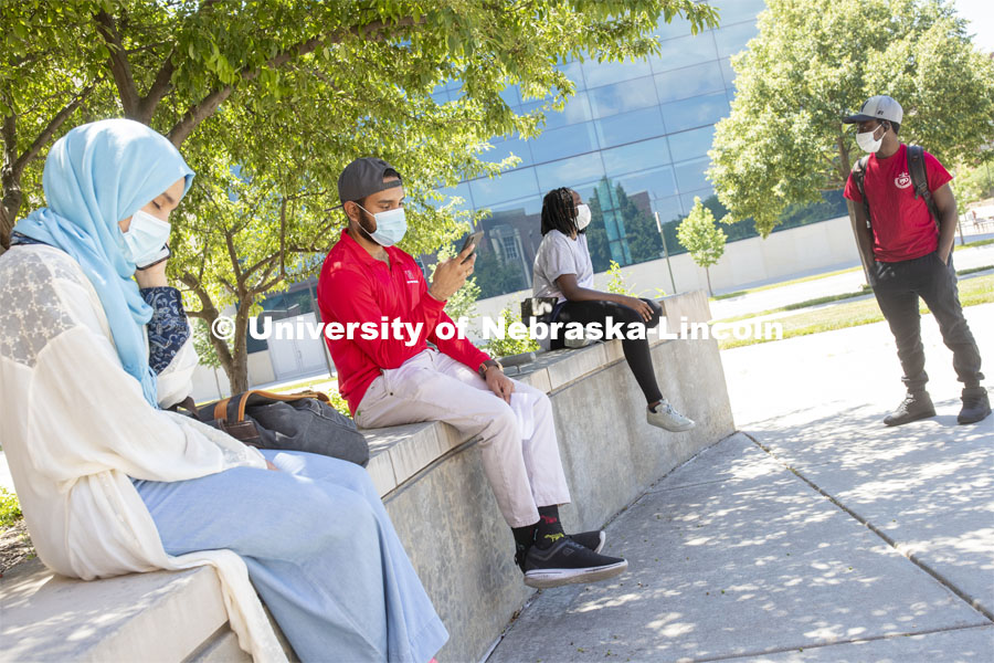 Aldi Airori checks his phone while wearing a mask and practicing social distancing outdoors. Photo shoot of students wearing masks and practicing social distancing. June 24, 2020. Photo by Craig Chandler / University Communication.