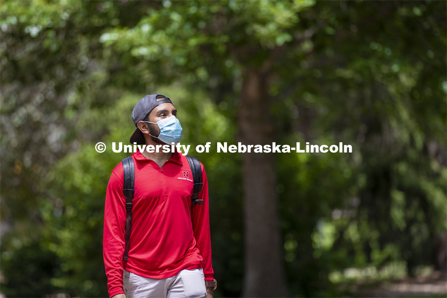 Aldi Airori walks across campus wearing his mask. Photo shoot of students wearing masks and practicing social distancing. June 24, 2020. Photo by Craig Chandler / University Communication.