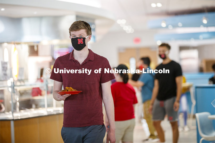 Young man wearing a Husker mask. Photo shoot of students wearing masks and practicing social distancing in dining services in Willa Cather Dining Center. July 1, 2020. Photo by Craig Chandler / University Communication.