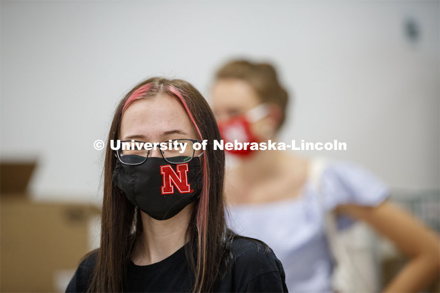A young woman’s Husker mask matches the red stripes in her hair. Photo shoot of students wearing masks and practicing social distancing in dining services in Willa Cather Dining Center. July 1, 2020. Photo by Craig Chandler / University Communication.