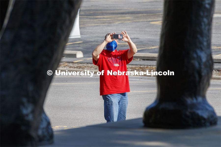 Evan Coleman, Computer, Technology and Web Support Associate with the CYFS group, takes a photo of Archie the mammoth wearing a mask. Archie the mammoth sculpture wears a mask outside of the University of Nebraska State Museum in Morrill Hall. The sculpture is one of many UNL campus sculptures wearing masks. Mask wearing statues on campus. July 7, 2020. Photo by Craig Chandler / University Communication.