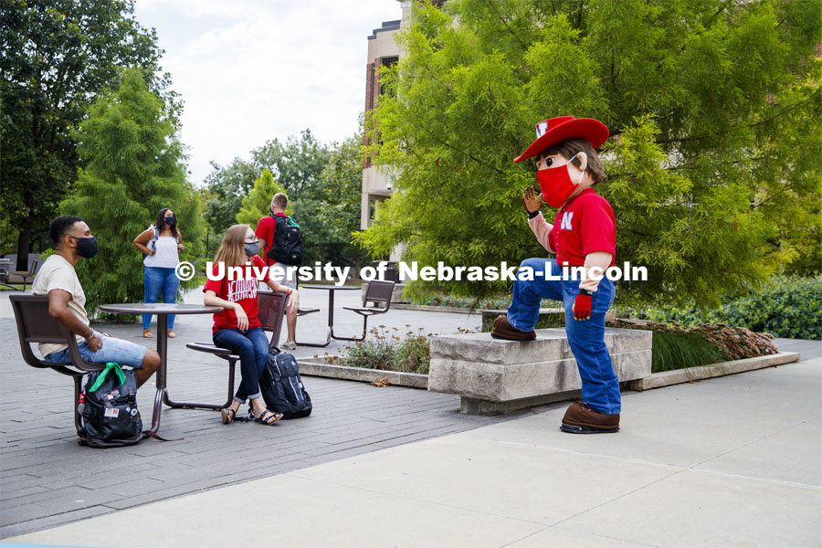Photo shoot of students with Herbie on city campus display mask wearing, social distancing. Students sitting at tables and hanging out with Herbie Husker. August 5, 2020. Photo by Craig Chandler / University Communication.