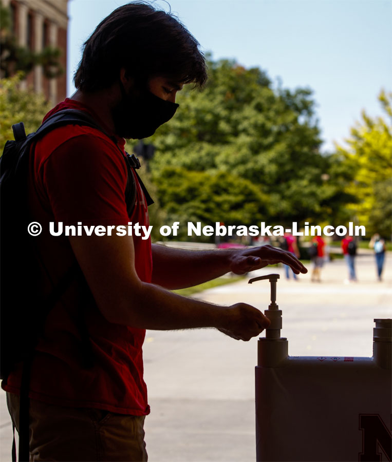 Photo shoot of students on city campus display mask wearing and hand sanitizing. A young man stops at a hand sanitizing station to clean his hands. August 5, 2020. Photo by Craig Chandler / University Communication.