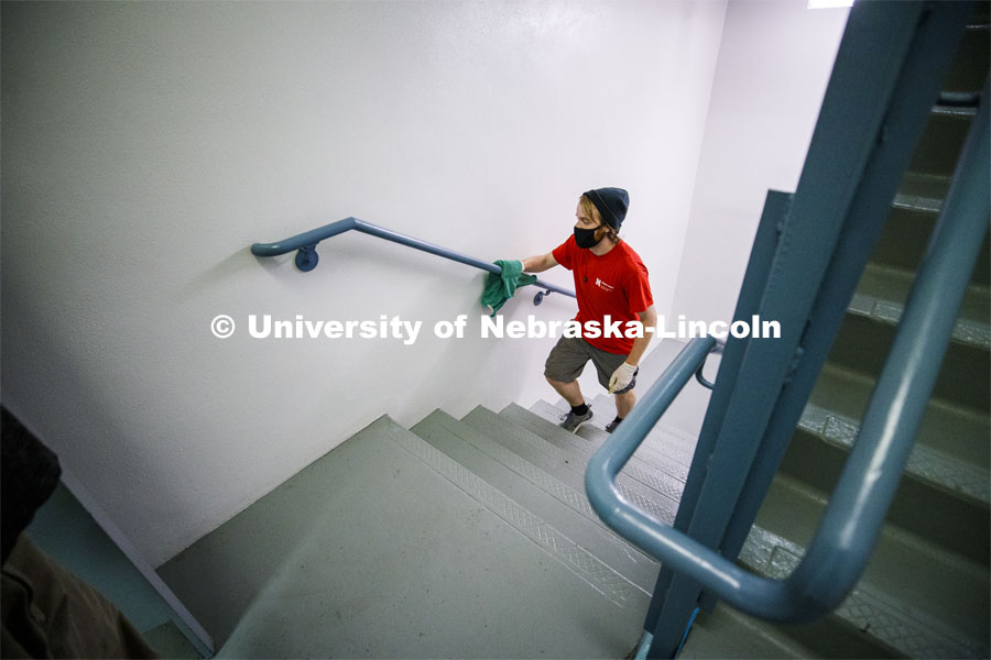 Kenny Shuman, a housing student worker, wipes down the stairway railings to keep move in clean. First day of residence hall move in. August 13, 2020. Photo by Craig Chandler / University Communication.