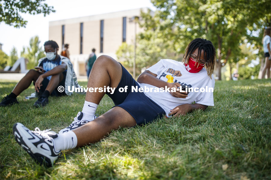 Da-Von George checks his phone while lying in the grass outside of the Woods Art Building before his photography class. First day for in-person learning for the fall semester. August 24, 2020. Photo by Craig Chandler / University Communication.