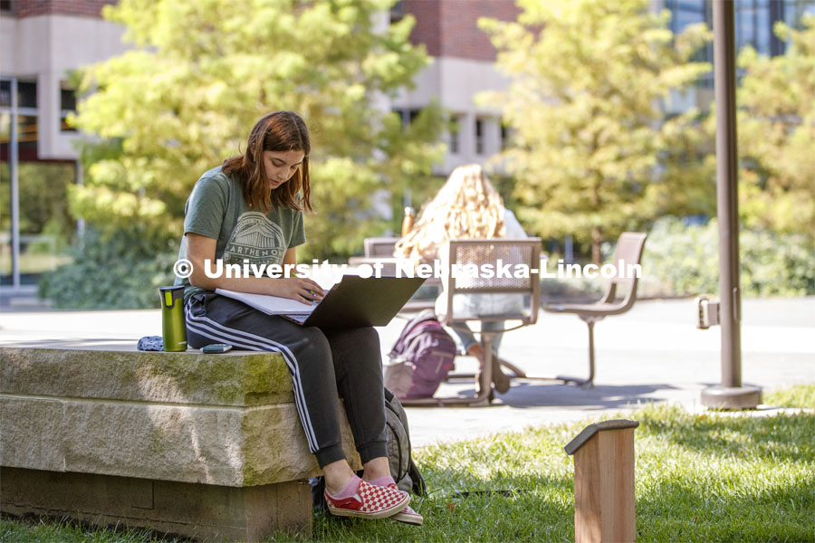 Isabella Kane zooms her class from a shady bench outside of Love Library's Adele Coryell Hall Learning Commons. City Campus. August 31, 2020. Photo by Craig Chandler / University Communication.