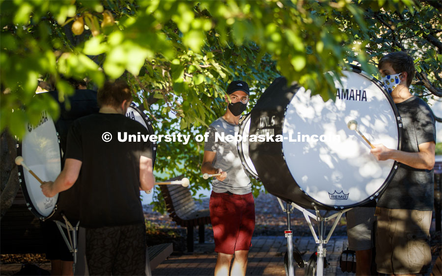 Carter Dawson directs the bass line practice under the trees outside the Lied Center. A sunrise serenade as the cymbals and bass line of the Cornhusker Marching Band practices outside Kimball Music Hall Tuesday morning, September 2, 2020. Photo by Craig Chandler / University Communication.