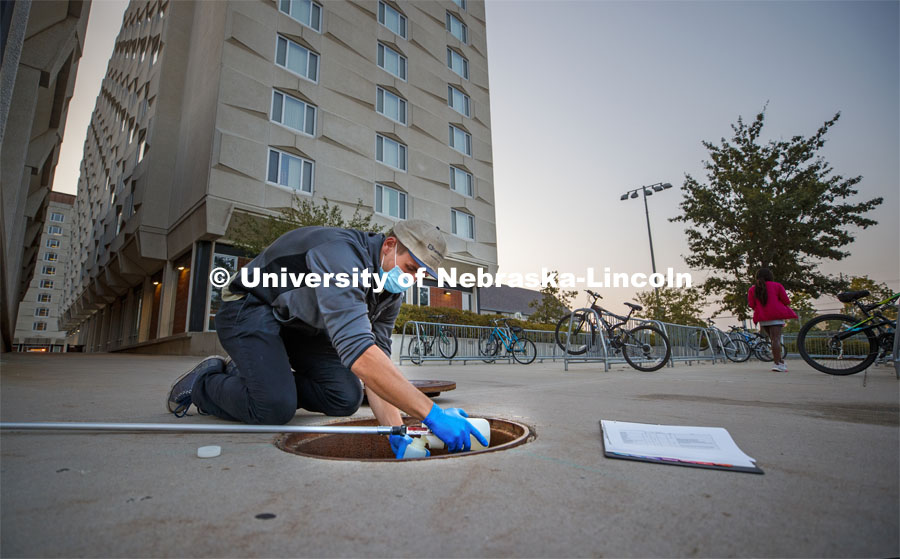 Spencer Perry, graduate student in environmental engineering, takes a wastewater sample from the sewer flowing from Smith Residence Hall. He and Shannon Bartelt-Hunt, professor in civil engineering, are sampling wastewater from UNL residence halls for COVID research. September 24, 2020 Photo by Craig Chandler / University Communication.