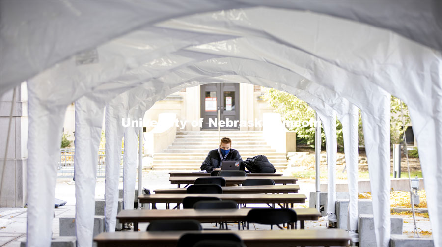 A young man studies in a tent outside. City Campus. October 28, 2020. Photo by Craig Chandler / University Communication.