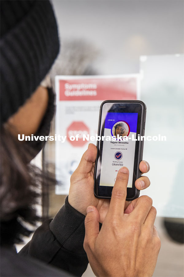 Yajyoo Shrestha shows the Safer Community app to be used as part of COVID testing on campus this spring.  Phone screen is simulated and may change slightly in the final rollout. January 8, 2021. Photo by Craig Chandler / University Communication.