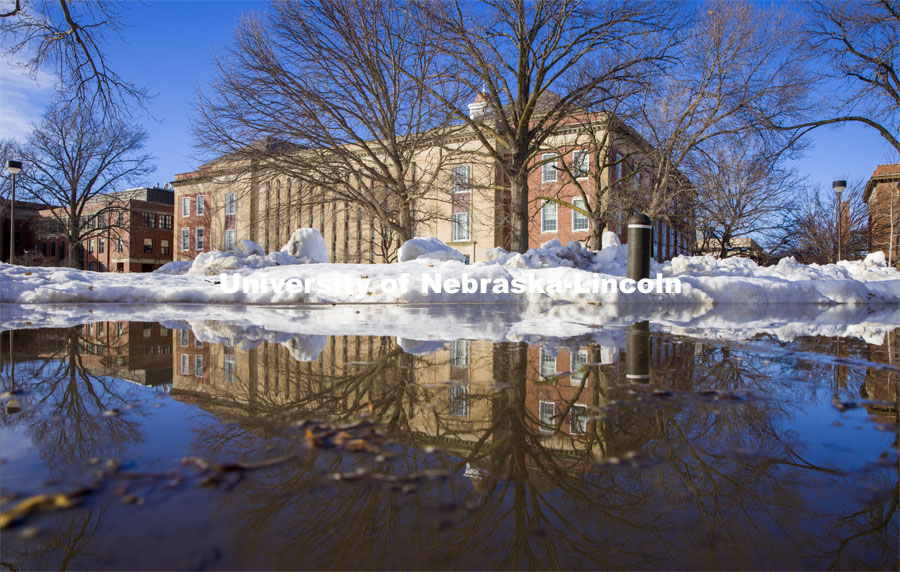 Love Library is reflected in a puddle along the drive behind Canfield Hall. February 22, 2021. Photo by Craig Chandler / University Communication.