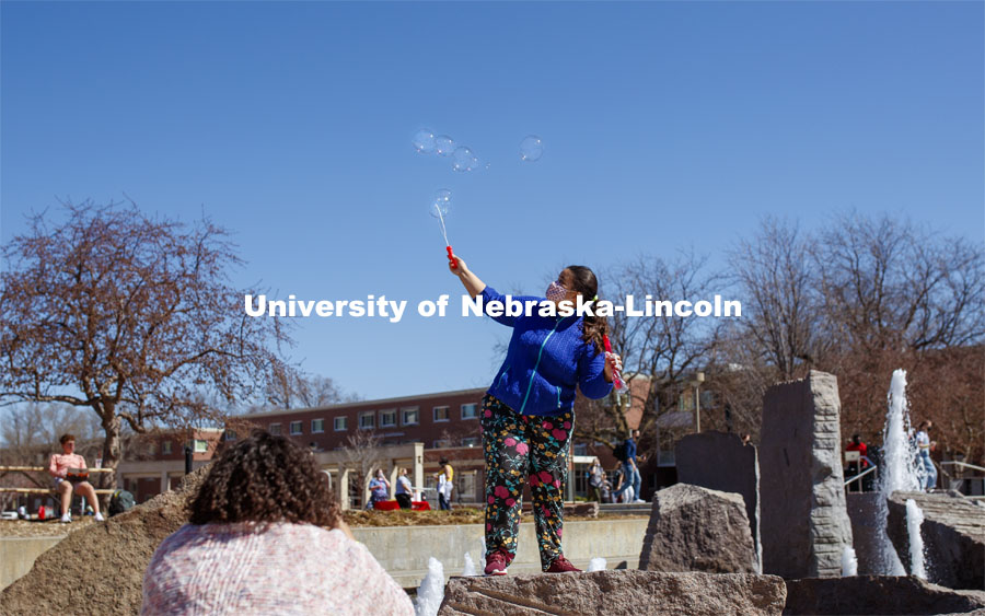 Julia Nogueira Duarte Campos blows bubbles while her friend takes a photo. Students have fun at the Spring Breakout, a midday festival with free games, music, and prizes. 300 free t-shirts for participants. March 29, 2021. Photo by Craig Chandler / University Communication.