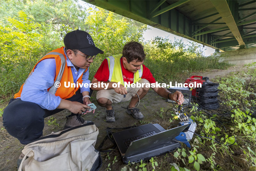 Ricky Wood, Associate Professor of Civil and Environmental Engineering, right, and Bowen Yang examine the cable connections that go to multiple sensors on the Platte River bridge. NOBL, the Nebraska Outdoor Bridge Lab as part of the College of Engineering is turning two bridge sites (for a total of three bridges) into a national research and educational facility for bridge health and testing. This bridge is across the Platte River on Highway 92 between Yutan and Omaha. August 9, 2021. Photo by Craig Chandler / University Communication.
