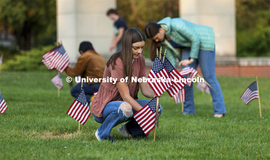 Madi Hadley, a freshman from Gunnison, Colorado, sets up flags in the green space north of the Nebraska Union to commemorate 9/11. Hadley said she has several family members on active duty, and this was a way she could honor their sacrifice. 9/11 memorials. September 9, 2021. Photo by Craig Chandler / University Communication.