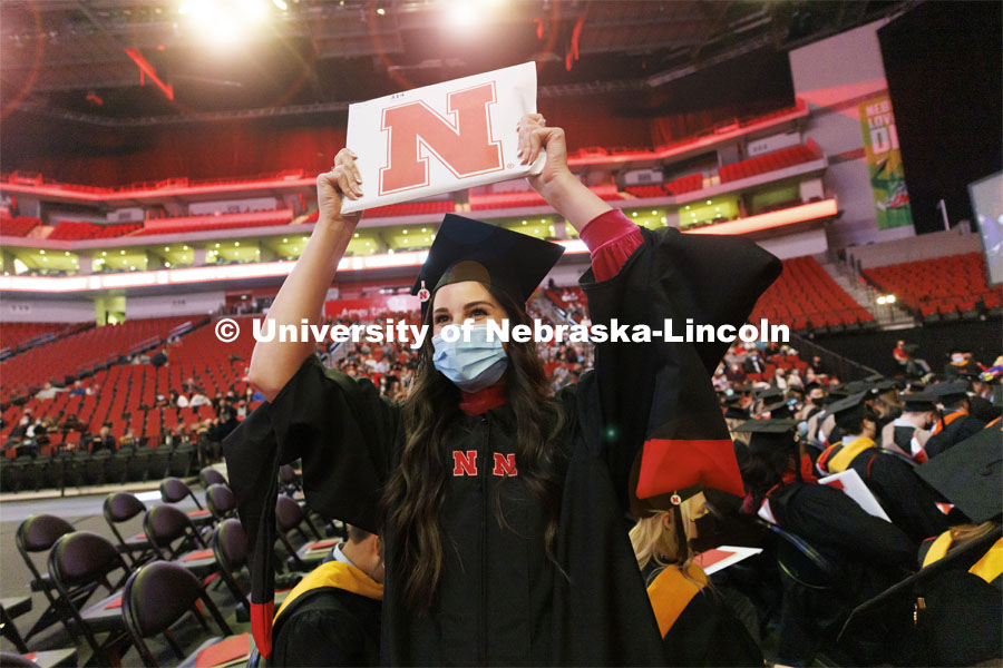Peyton Millard shows off her new masters diploma to her friends and family in the arena. Graduate Commencement at Pinnacle Bank Arena. December 17, 2021. Photo by Craig Chandler / University Communication.