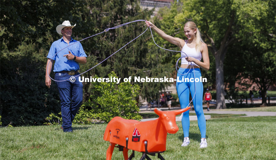 Gracie Jones, a freshman from Chadron, tries her hand at roping as Rodeo Club coach Marshal Peterson watches. Club Fair in the green space by the Nebraska Union at City Campus. More than 120 recognized student organizations (RSOs) to join for social, professional and leadership interests. RSO members and officers will be on hand to provide details about their organization and answer questions from prospective new members. August 24, 2022. Photo by Craig Chandler / University Communication.