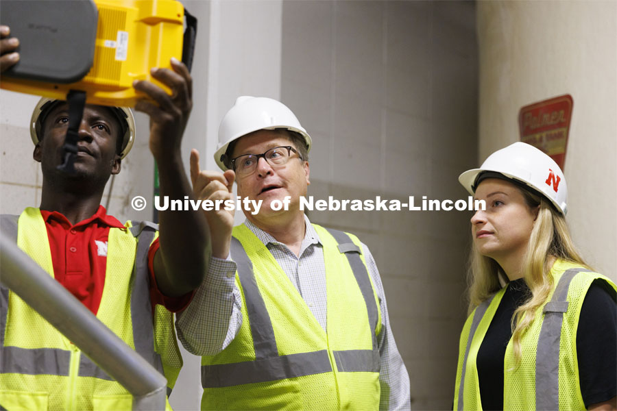 Bruce Dvorak, center, Professor of Civil and Environmental Engineering, coaches Yves Cedric Tamwo Noubissi, left, senior in Mechanical Engineering, and Sussan Moussavi, graduate student in Civil Engineering, in the use of a Fluke Precision Acoustic Imager, used to detect leaks of gases and vacuum from pipes and tanks. They are working inside Lincoln’s Theresa Street Wastewater Treatment Plant. September 23, 2022. Photo by Craig Chandler / University Communication.
