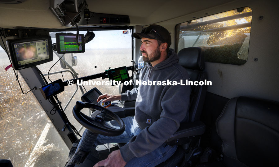 Surrounded by acres of popcorn outside his combine cab and multiple computer monitors inside the cab, Andrew McHargue harvests popcorn east of Chapman, Nebraska. Preferred Popcorn grows popcorn near Chapman, Nebraska and throughout the area. It is headed by Norm Krug. October 13, 2022. Photo by Craig Chandler / University Communication.