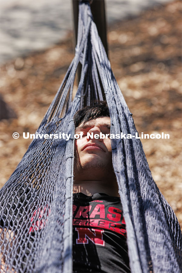 Ben Swidler, a sophomore from Buffalo Grove, Illinois, relaxes in the hammocks outside the Nebraska Union. Spring on City Campus. April 10, 2023. Photo by Craig Chandler / University Communication.