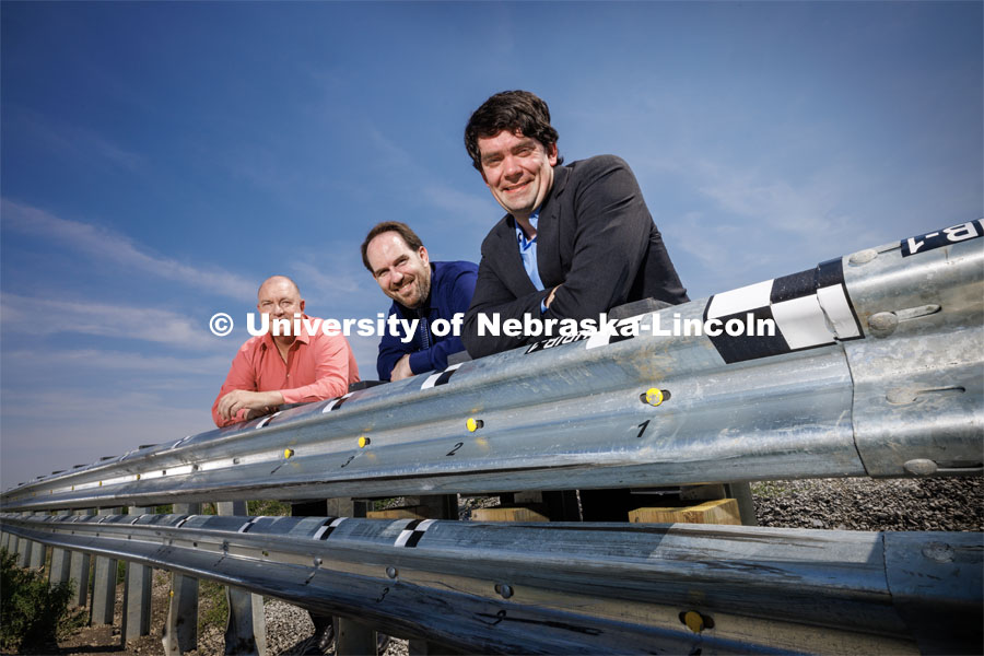 Husker Cody Stolle (right), Josh Steelman (center) and Ronald Faller lean against a guardrail developed at the university-housed Midwest Roadside Safety Facility that might be part of the solution to better protection for soldiers at military checkpoints. Cody Stolle, Research Assistant Professor and Assistant Director of the Midwest Roadside Safety Facility is leading a group researching better checkpoint barriers to help the Department of Defense. Photo used for 2022-2023 Annual Report on Research at Nebraska. June 5, 2023. Photo by Craig Chandler / University Communication.