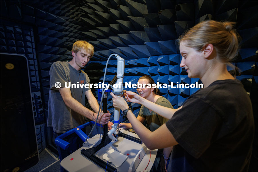 Sean Crimmins (from left), a senior mechanical engineering major; Erika Smith, a recent Husker graduate and Virtual Incision employee; and Rachael Wagner, a Husker graduate and Virtual Incision employee, adjust the robotic arm on a stand in a chamber for electromagnetic compatibility (EMC) and electromagnetic interference (EMI) testing. Virtual Incision is sending its surgical robot to the International Space Station. Virtual Incision employees had the arm and the case that will take it into space tested at Lincoln’s NCEE labs. August 11, 2023. Photo by Craig Chandler / University Communication.
