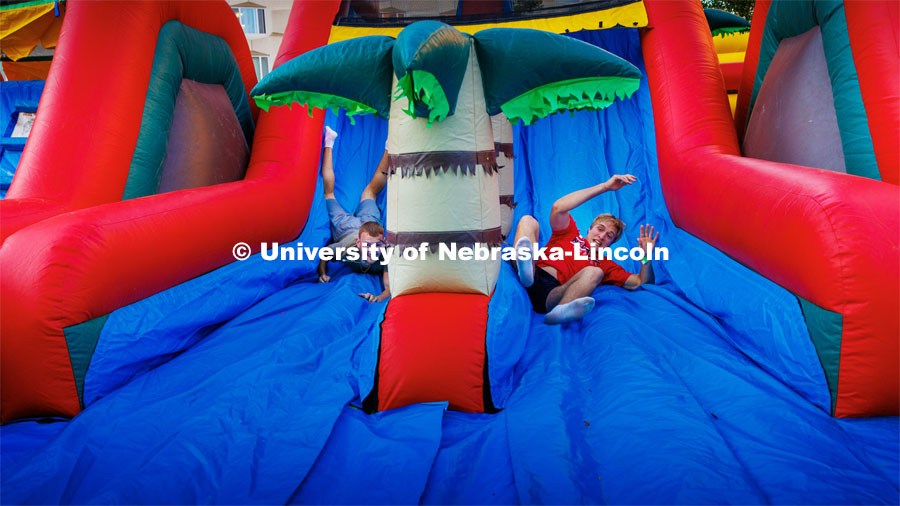 Cooper Garrett of Grand Island, right, rolls down the inflatable maze ahead of his competition. Block party at Harper Schramm Smith. August 17, 2023. Photo by Craig Chandler / University Communication.