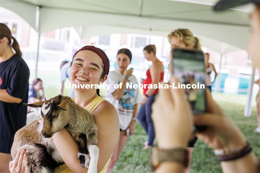 A participant in the goat yoga poses for a photo with one of the goats. Wellness Fest in front of the Nebraska Union and on the green space. August 19, 2023 Photo by Craig Chandler / University Communication.