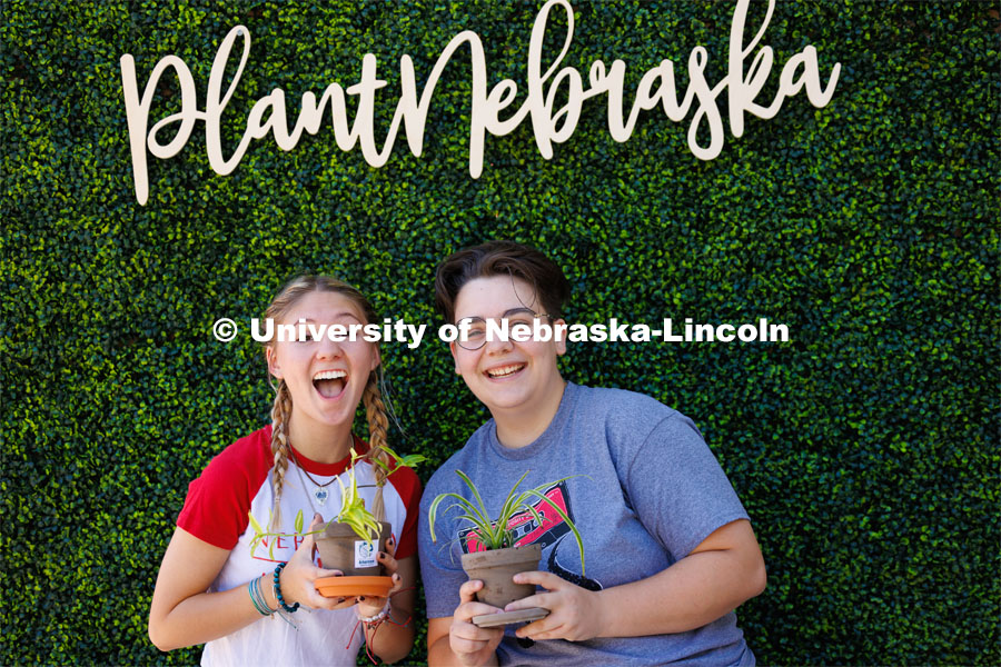 Shae Mitchell, a freshman from Edison, Nebraska, center, and Emmy Oldham, a freshman from Wellfleet, Nebraska, have their picture taken at the Plant Nebraska booth. Wellness Fest in front of the Nebraska Union and on the green space. August 19, 2023. Photo by Craig Chandler / University Communication.