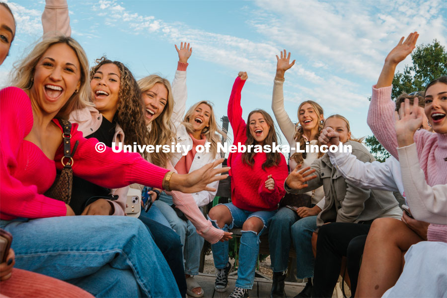 Members of the Husker Cheer Squad on a hay rack ride at Roca Berry Farm. About Lincoln at Roca Berry Farm. October 22, 2023. Photo by Matthew Strasburger / University Communication.