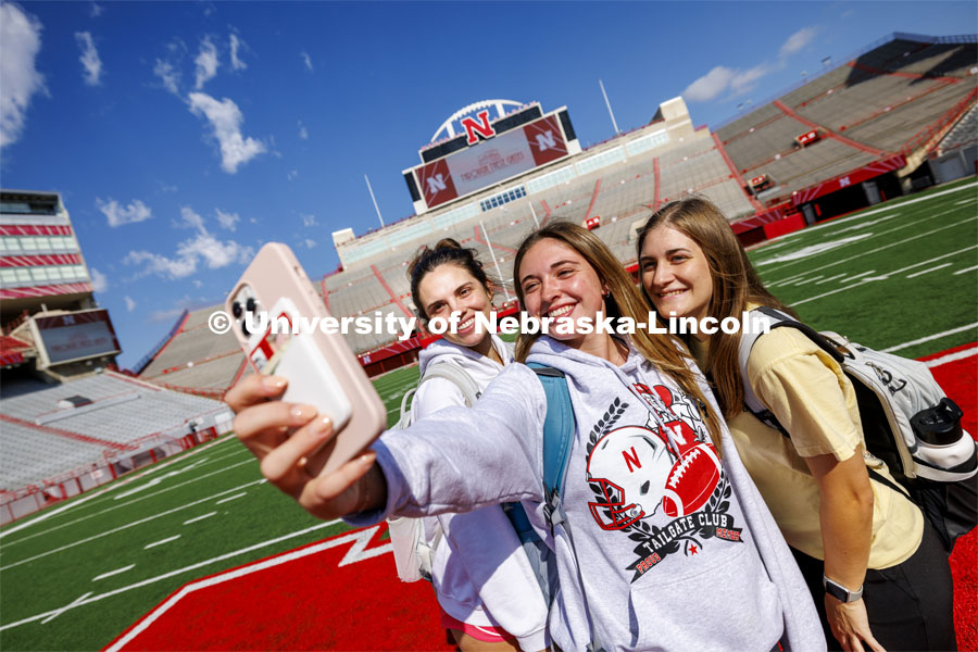 Sydney White, left, Morgan Wiseman and Gretchen Hodge, all juniors and Delta Delta Delta sorority members, take a selfie on the N in Memorial Stadium during the birthday party. Memorial Stadium 100th birthday party at the stadium. The free public event featured cake and visitors could walk onto the field. October 23, 2023. Photo by Craig Chandler / University Communication.
